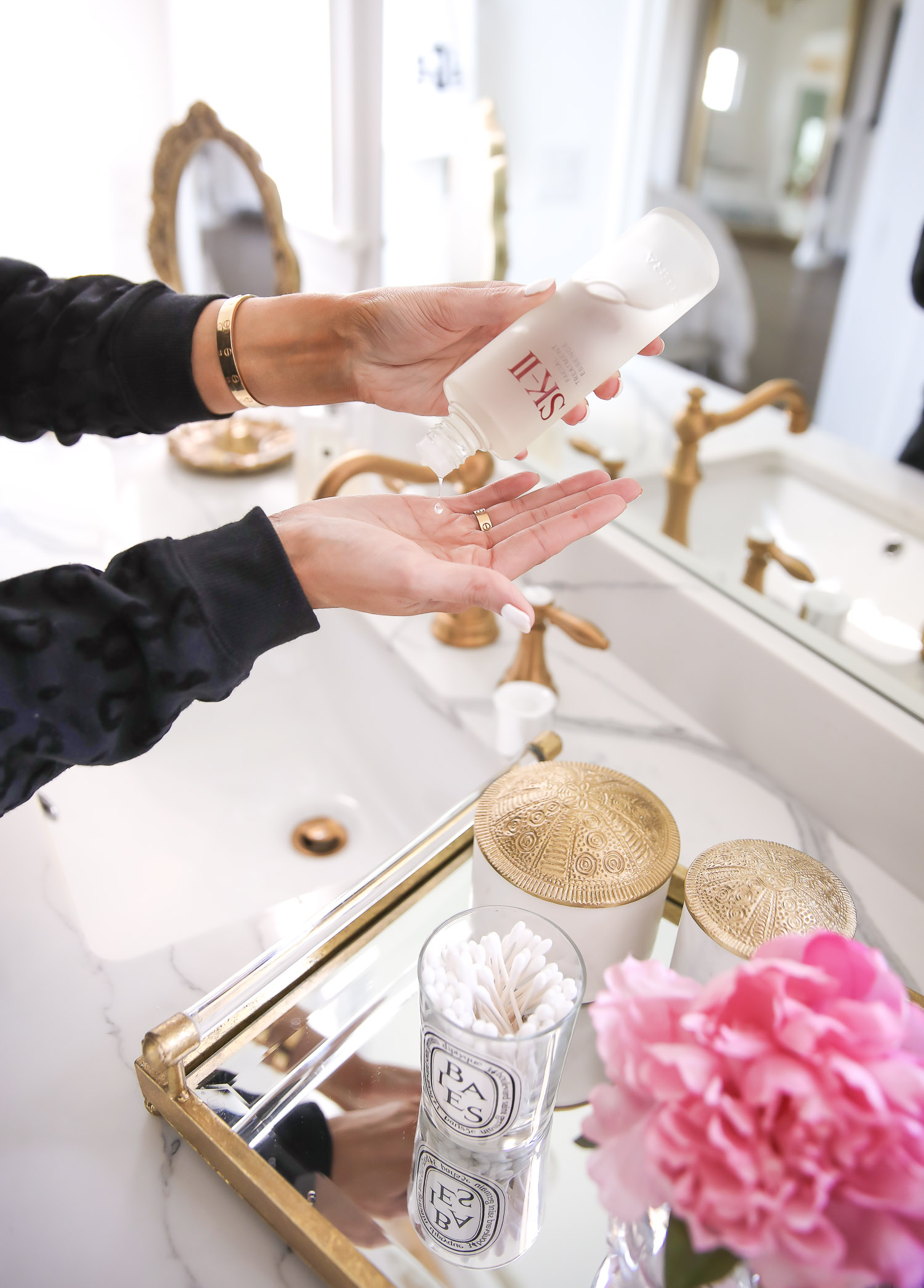 SK II Pitera Essence by popular US beauty blog, The Sweetest Thing: image of a woman wearing a black leopard print sweatshirt, black leopard print sweat pants and pink fuzzy slippers while pouring some SK II Pitera Essence into her hand. 