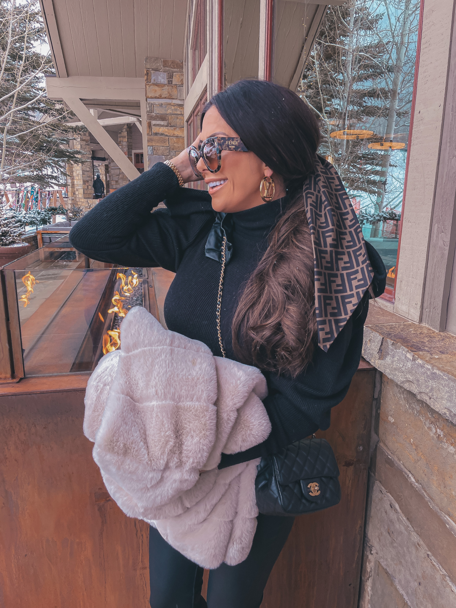 fendi hair scarf scrunchie, Louis Vuitton Louise Hoop Earrings, Fendi Roma Sunglasses, Emily Gemma, the sweetest thing blog |Jackson Hole Winter by popular US fashion blog, The Sweetest Thing: image of Emily Gemma wearing a BB Dakota tan faux fur coat, black Express ruffle shoulder top, Fendi sunglasses, Black BlankNYC faux leather leggings, Louis Vuitton boots, Fendi hair scarf, Louis Vuitton earrings, and a Chanel black quilted purse.