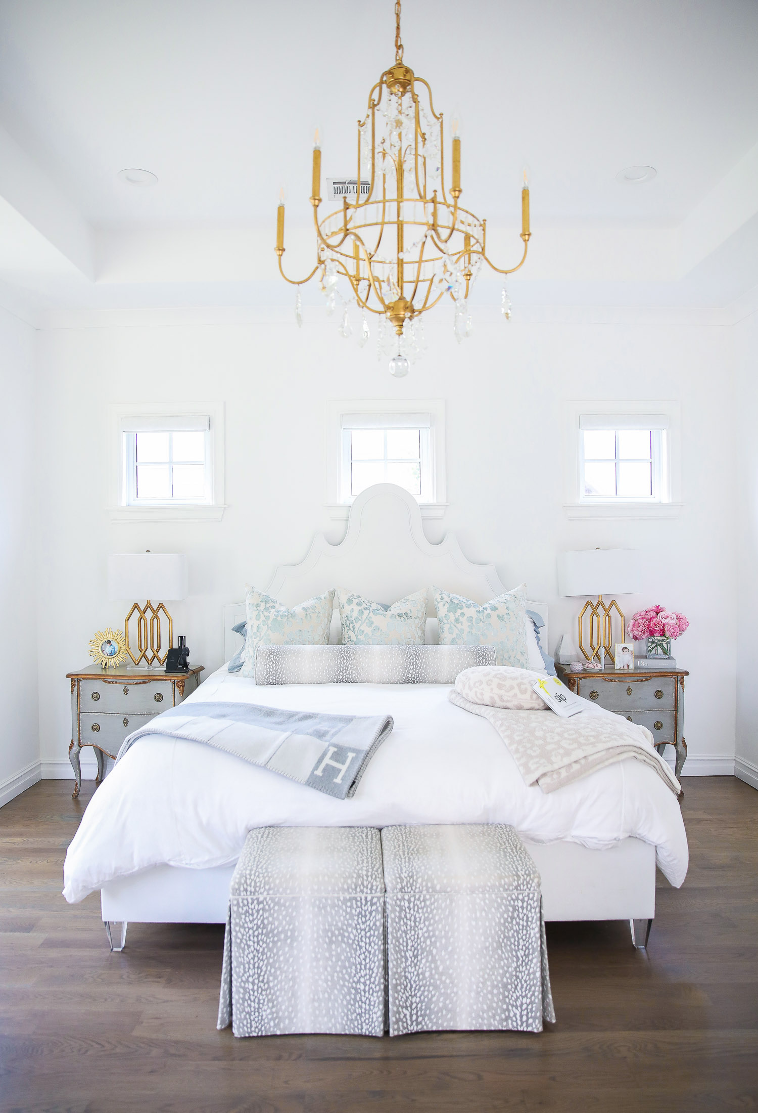 Emily gemma master bedroom, little design co pillows bolster, Hermes Avalon throw blanket gray, Nordstrom anniversary sale home must haves 2021, nsale barefoot dreams blanket pillows review, parfum de marly set |  Nordstrom Anniversary Sale 2021 by popular US life and style blog, The Sweetest Thing: image of a master bedroom with mirrored end tables, gold base lamps, glass vase filled with pink peonies, Voulspa candle, and bed with a white fabric headboard, white bedding, and grey and white antelope print throw pillows. 